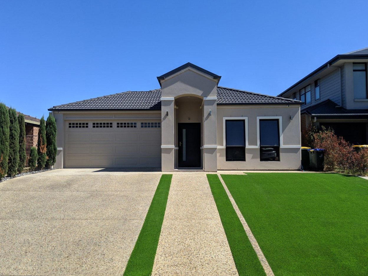 Artificial Turf next to a driveway in the front yard of a large home