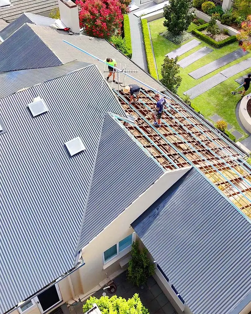bird's eye view of roofing workers re-roofing a house with grey colorbond sheets