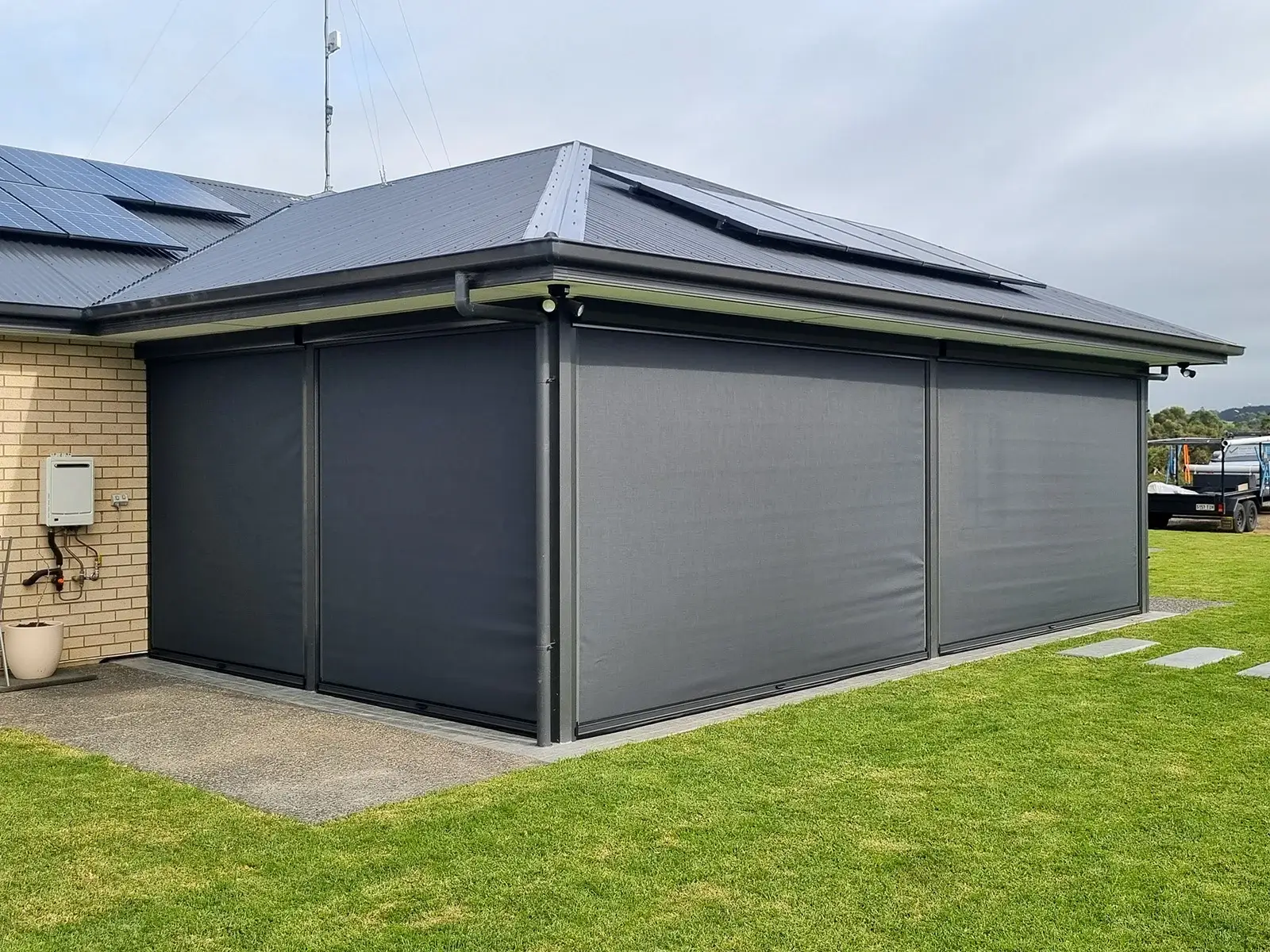 House with Manual Ziptrak Blinds fully extended, providing weather protection and privacy to the outdoor area on a cloudy day.