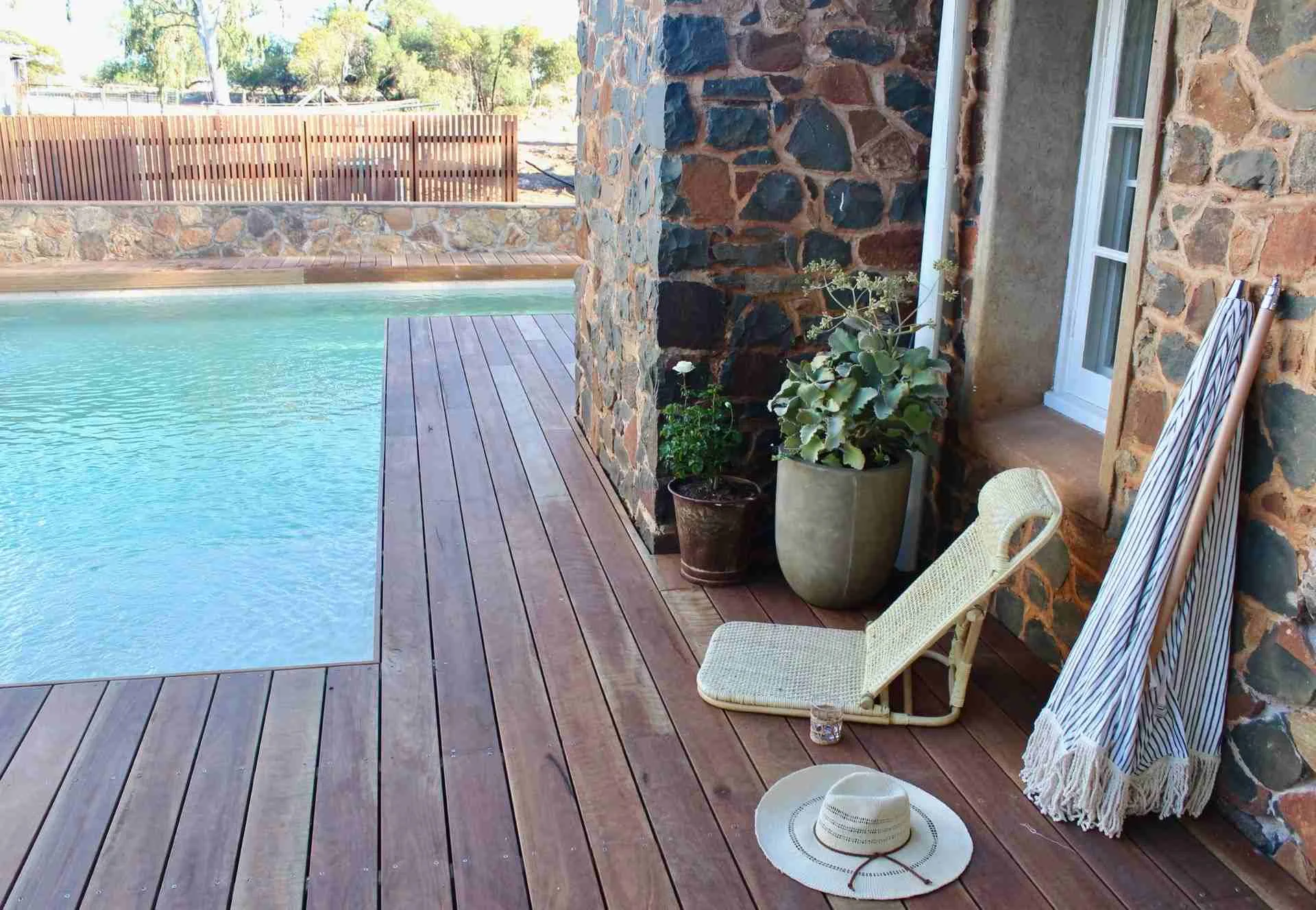 timber decking by a swimming pool, with a fold out chair and hat.