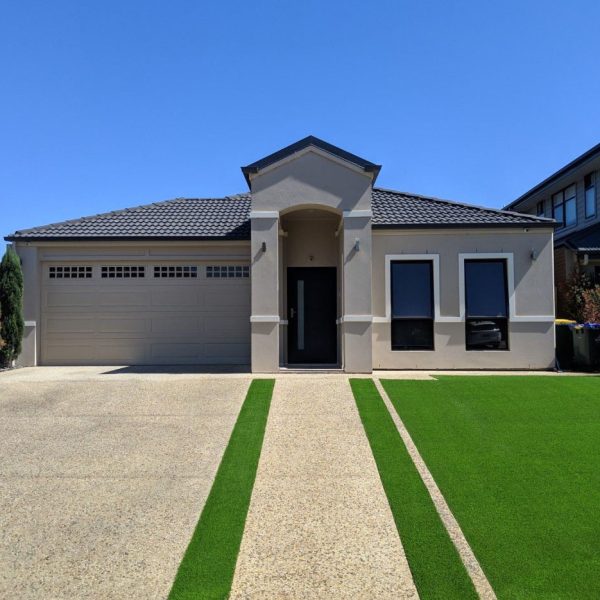 Artificial Turf next to a driveway in the front yard of a large home