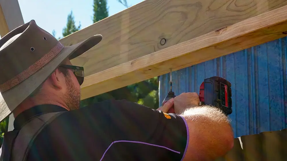 Just Quality installer drilling into a timber pergola beam.
